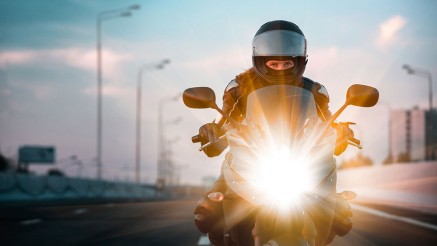 Gothaer Motorradversicherung: Motorradfahrer fährt in der Dämmerung mit seinem Motorrad auf der Straße.
